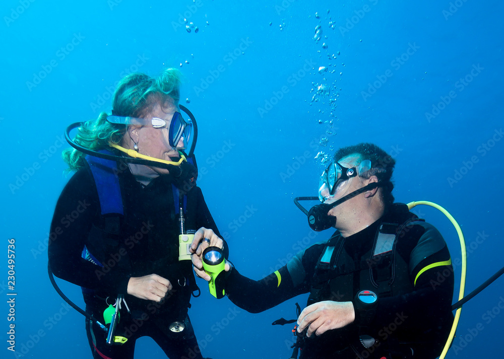 Happy couple scuba divers hovering together on a safety stop Happy couple scuba divers hovering together on a safety stop