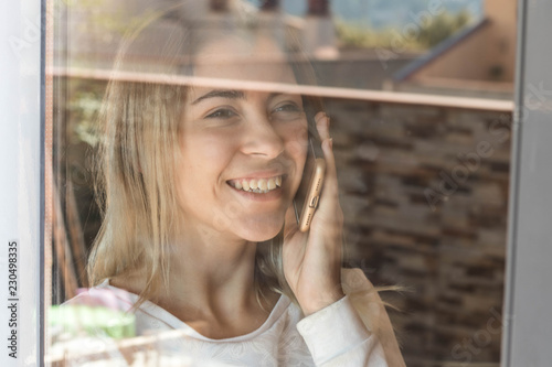 Girl with a smartphone next to a window photo