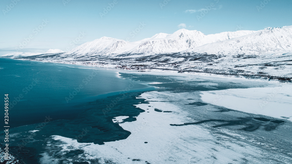 Frozen body of water surrounded by snow capped mountains Frozen body of water surrounded by snow capped mountains