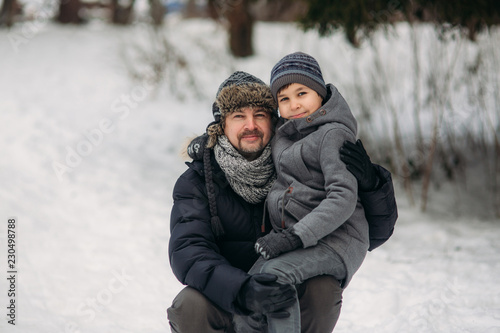 Happy father with his son walks through the park in the snowy winter weather
