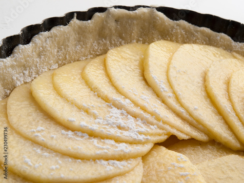 Detalle en primer plano de una tarta de manzana en su molde  y sus lonchas crudas 3