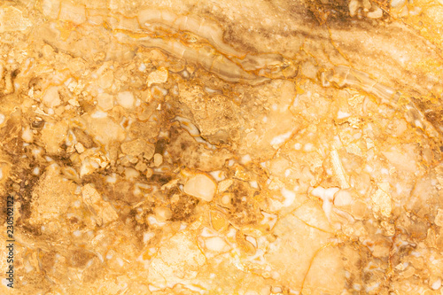 Stone gold wall marble texture for background. Natural marble stone texture in warm colors. Background with small waves and a round pattern. Brown, orange, gold, yellow and beige shades.