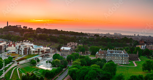 View over the Palace of Holyroodhouse, Scottish Parliament and Calton Hill under orange sunset sky in Edinburgh, Scotland photo