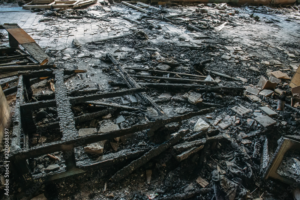 Remains of burnt wooden furniture on the floor of building after fire Remains of burnt wooden furniture on the floor of building after fire