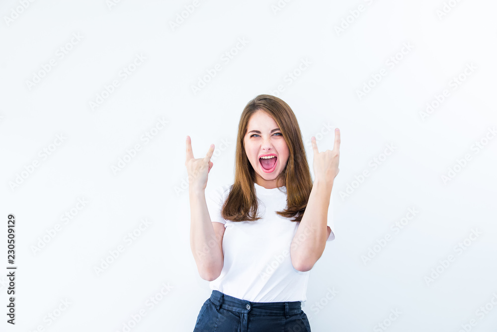 Happy excited young woman showing the sign of rock and roll sigh isolated on white background. Emotional girl flirting at camera and showing dancing gesture.Positive emotion expression. Copy space. Happy excited young woman showing the sign of rock and roll sigh isolated on white background. Emotional girl flirting at camera and showing dancing gesture.Positive emotion expression. Copy space.