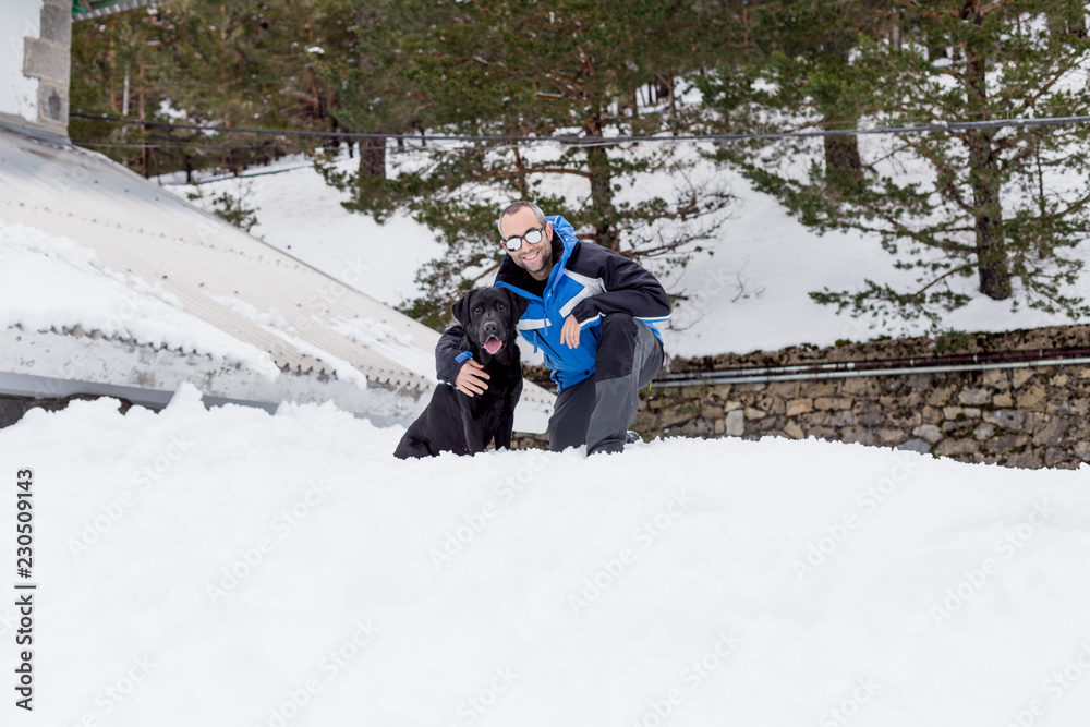 portrait of a beautiful black labrador and his owner outdoors in the mountain having fun. Pets in nature