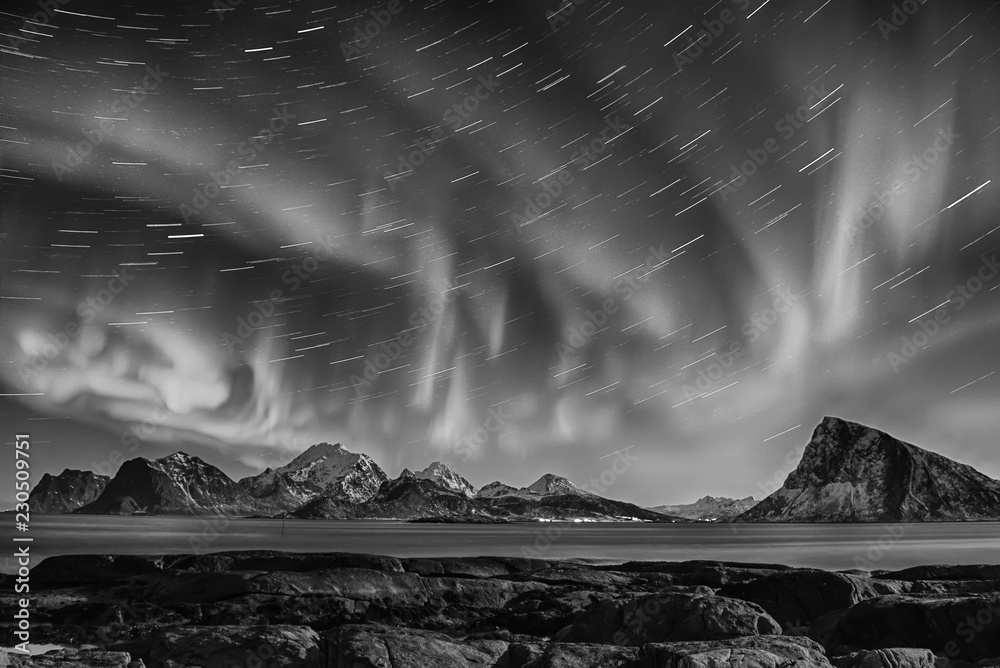 Northern Lights, Aurora Borealis shining in night starry sky with star  tracks at winter Lofoten Islands, Norway. Black and white. Stock Photo |  Adobe Stock