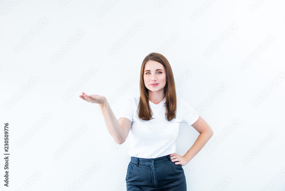 Portrait of Beautiful smiling Brunette young woman in casual T-shirt showing empty copy space on the open hand palm. Proposing a product. Gesture for advertisement. Isolated on white background. Portrait of Beautiful smiling Brunette young woman in casual T-shirt showing empty copy space on the open hand palm. Proposing a product. Gesture for advertisement. Isolated on white background.