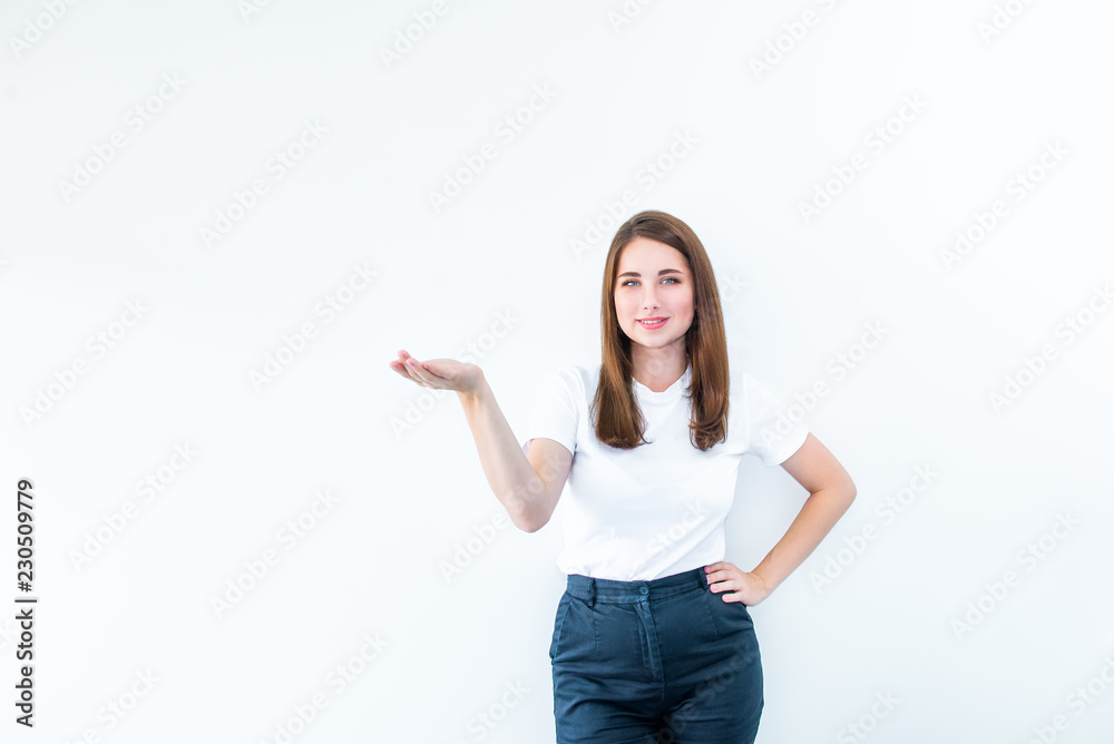 Portrait of Beautiful smiling Brunette young woman in casual T-shirt showing empty copy space on the open hand palm. Proposing a product. Gesture for advertisement. Isolated on white background. Portrait of Beautiful smiling Brunette young woman in casual T-shirt showing empty copy space on the open hand palm. Proposing a product. Gesture for advertisement. Isolated on white background.