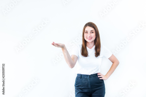 Portrait of Beautiful laughing Brunette young woman in casual T-shirt showing empty copy space on the open hand palm. Proposing a product. Gesture for advertisement. Isolated on white background.