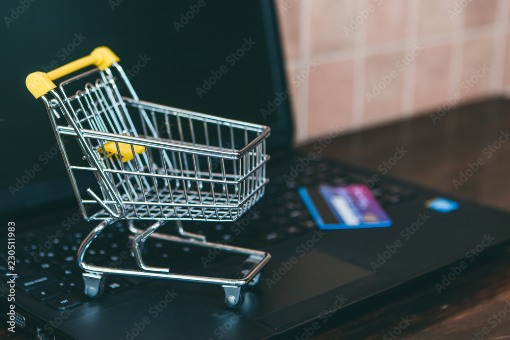 Supermarket shopping online concept. Trolley on a laptop keyboard.