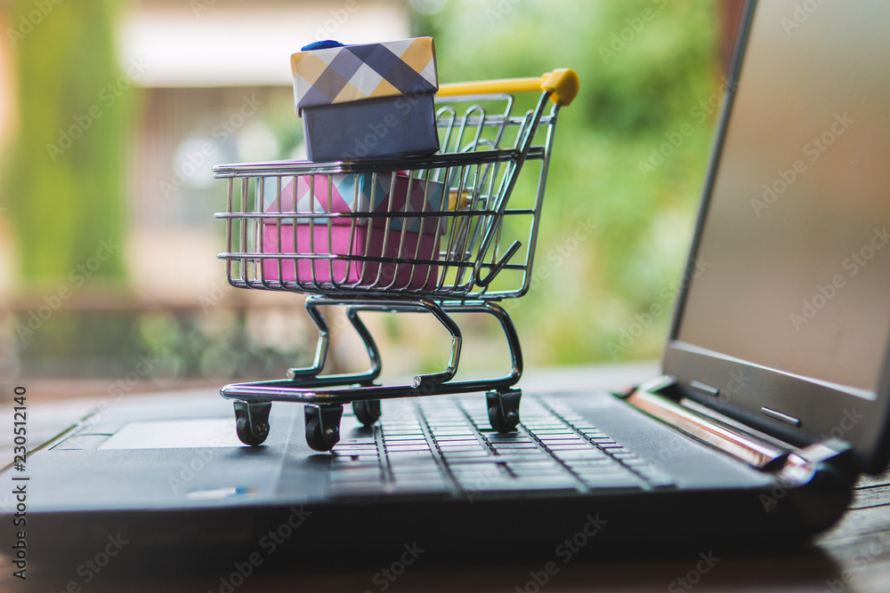 Black Friday and Cyber Monday concept. Some gifts inside a trolley on a laptop keyboard. E-commerce idea.