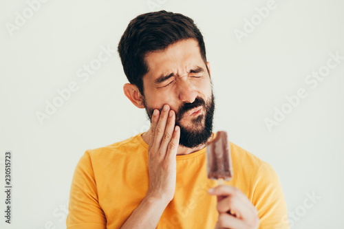 Man have sensitive teeth with ice on white background photo