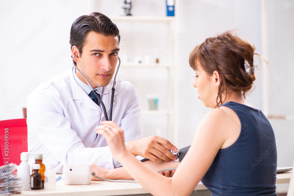 Young doctor checking woman's blood pressure