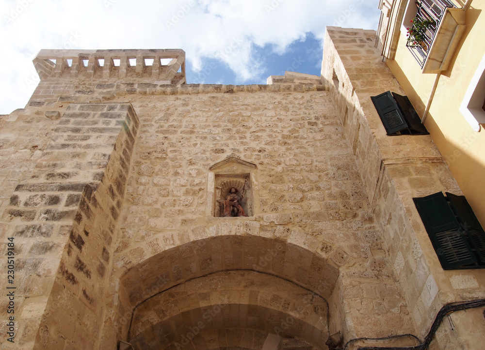 close up of the historic stone city gate in Mahon Menorca against a blue sunlit sky close up of the historic stone city gate in Mahon Menorca against a blue sunlit sky