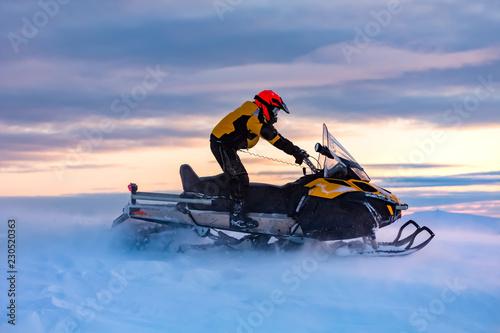 A man is ridind snowmobile in mountains. photo