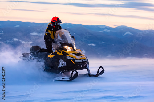 A man is ridind snowmobile in mountains. photo