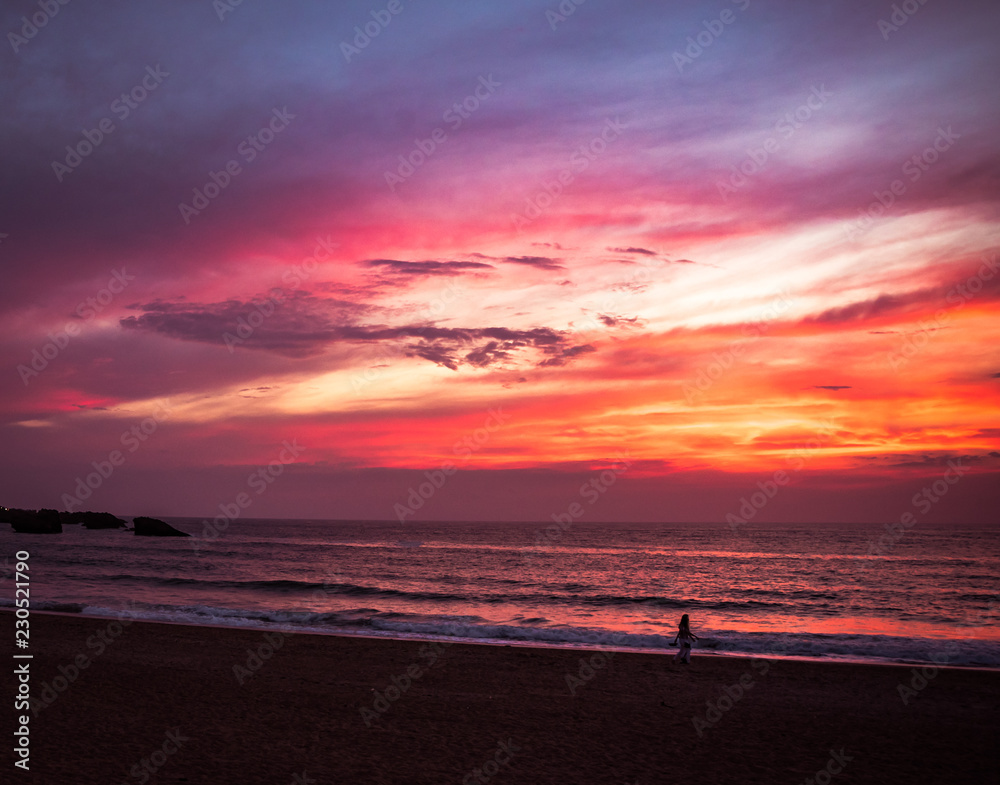 Girl enjoying a summer sunset on the beach called Grand Plage in Biarritz, France .