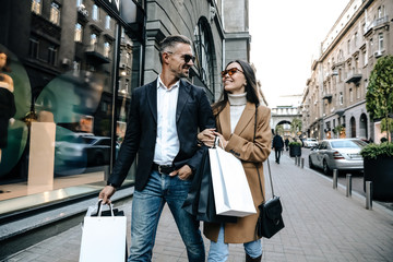 Shopping. Black Friday. Couple. Love. Man and woman with shopping bags are smiling while walking down the street