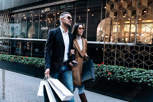 Shopping. Black Friday. Couple. Love. Man and woman with shopping bags are talking and smiling while walking down the street