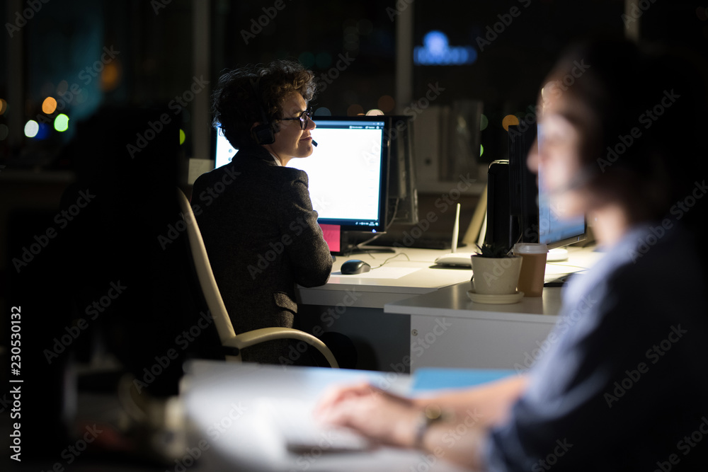 Back view portrait of female customer service operator smiling happily while working at night, copy space