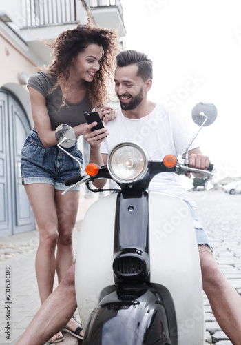 Happy young couple having summer trip on a scooter