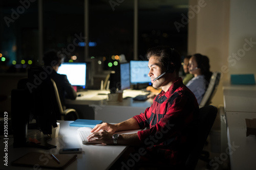Side view portrait of male help desk operator working at night, copy space