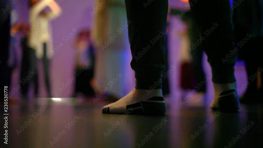 Low angle of woman feet in sock dancing - Filmed from the ground, at night, in a round room with colored lights