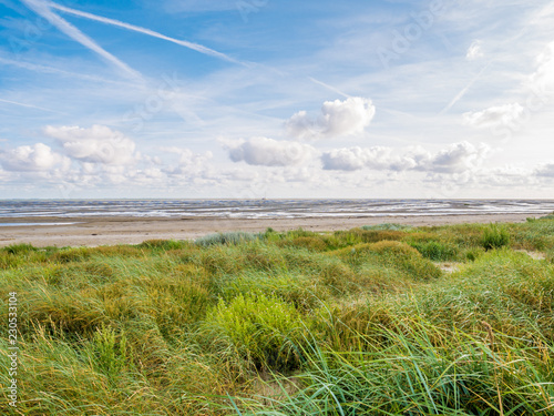 Coastline with dunes, beach and boat dried out on sand flats of Waddensea, Boschplaat, Terschelling, Netherlands photo