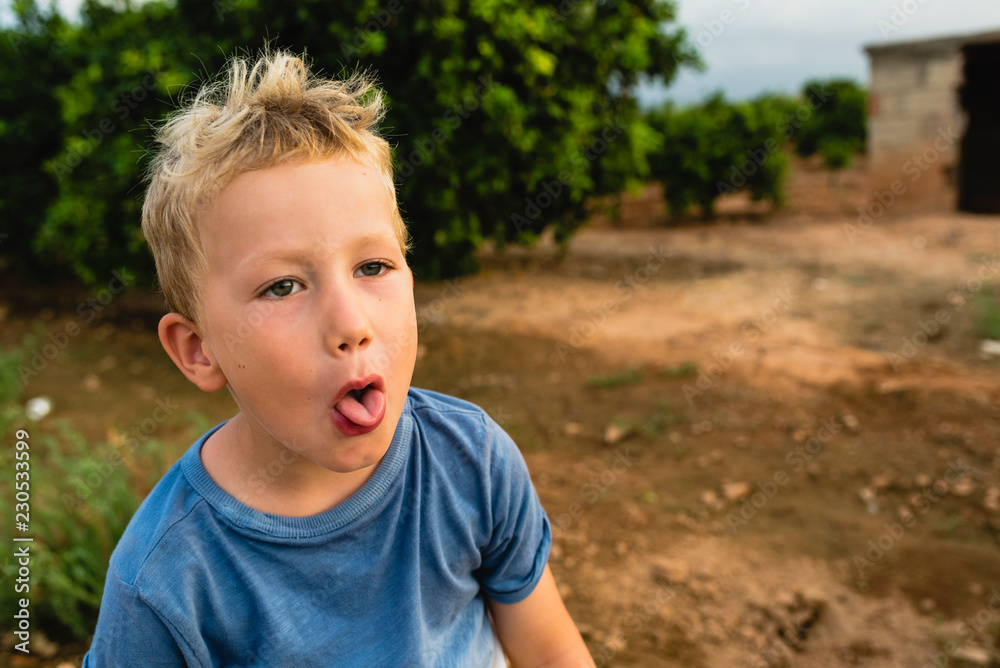 Blond boy making funny faces outdoors Blond boy making funny faces outdoors