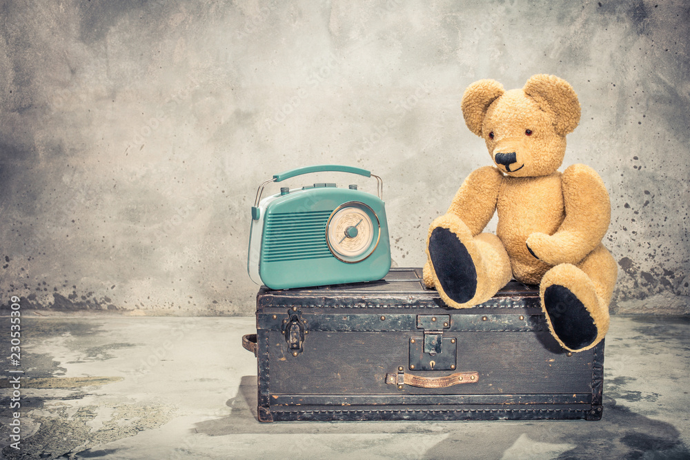 Φωτογραφία Retro radio and Teddy Bear toy sitting on old aged classic travel trunk with leather handles circa 1900s