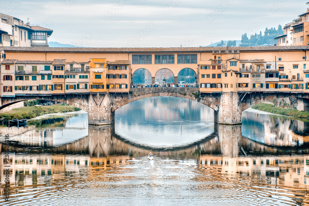 Remando no rio Arno. Vista da ponte vecchio em Florença e um atleta remando no rio.