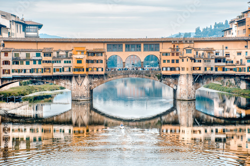 Remando no rio Arno. Vista da ponte vecchio em Florença e um atleta remando no rio. photo