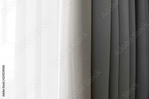 Close-up view of bright curtain in thin and thick vertical folds made of dense fabric.Textured abstract backgrounds and wallpapers.Materials and textiles.