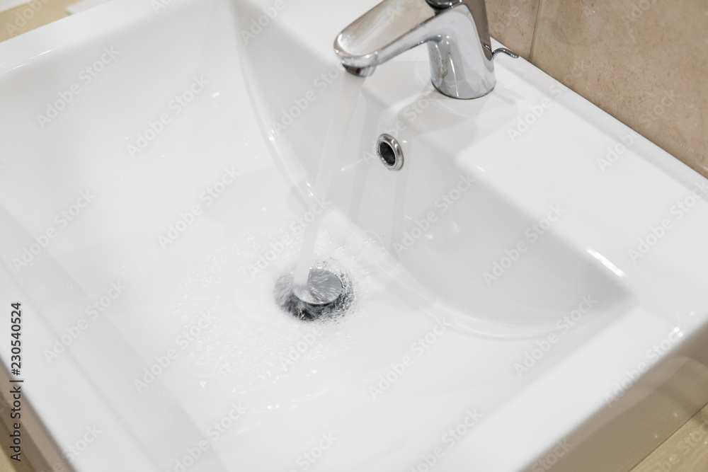 Bathroom sink tap with running water. Single lever monobloc chrome mixer tap on bathroom sink. Bathroom sink tap with running water. Single lever monobloc chrome mixer tap on bathroom sink.