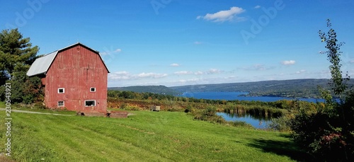 Vintage Abandoned Wooden Red Barn with Wine Vineyard and Lake in Background photo