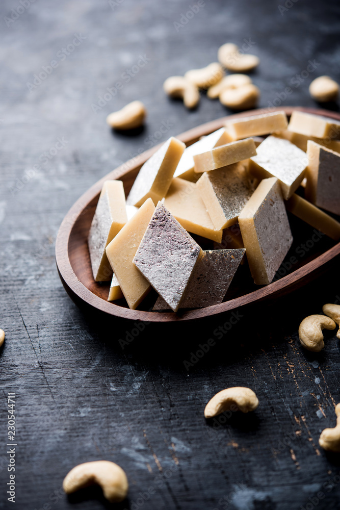 Fototapeta premium Kaju Katli is a Diamond shape Indian sweet made using cashew sugar and mava, served in a plate or bowl over moody background. selective focus