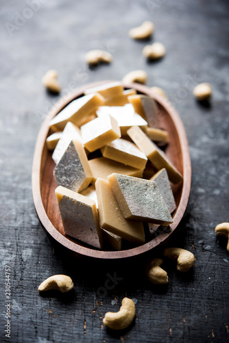 Kaju Katli is a Diamond shape Indian sweet made using cashew sugar and mava, served in a plate or bowl over moody background. selective focus