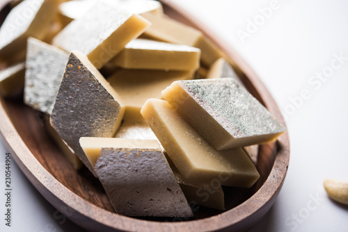 Kaju Katli is a Diamond shape Indian sweet made using cashew sugar and mava, served in a plate or bowl over moody background. selective focus photo