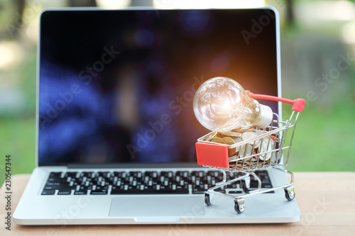 trolley and coins with electric glass bulb on computer, idea for shopping and online payment using as business background..