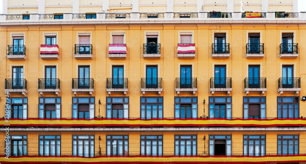 Yellow facade with many windows decorated with the spanish flag