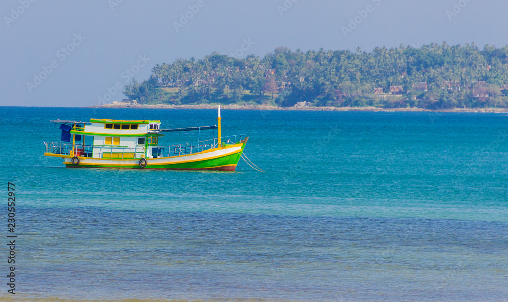 Fototapeta premium multi-colored boat moored at the shore floats on the sea