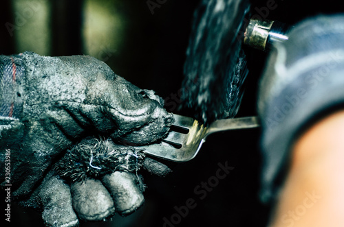 Jeweler working on silver fork in his workshop. Detail of silver polishing. photo