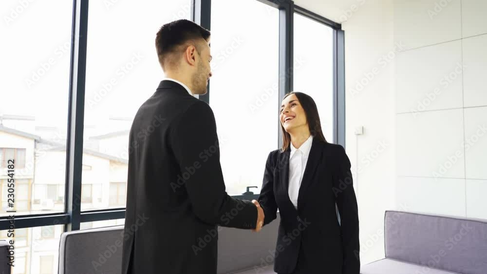 4K. Office work meeting. Two business partner, man and woman, shake hands and smile 4K. Office work meeting. Two business partner, man and woman, shake hands and smile