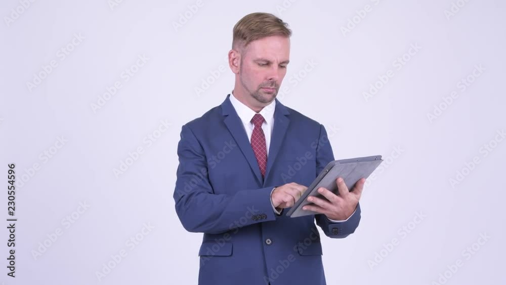 Happy blonde businessman thinking while using digital tablet Happy blonde businessman thinking while using digital tablet