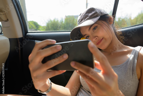 Canvas Print Young beautiful Asian woman using mobile phone in car