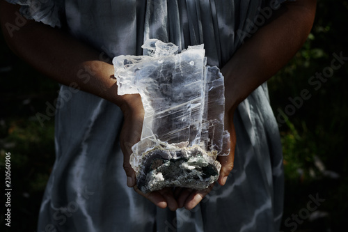 Close up of a woman holding a dark, powerful selenite crystal on geode photo