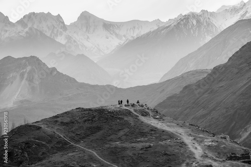Mountain range in Nargar with golden peak. People standing on a hill waiting for rising sun at Eagle's nest viewpoint. Hunza valley, Pakistan.