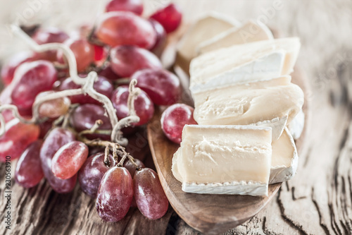 Organic homemade white brie cheese with pink grapes on a wooden Board