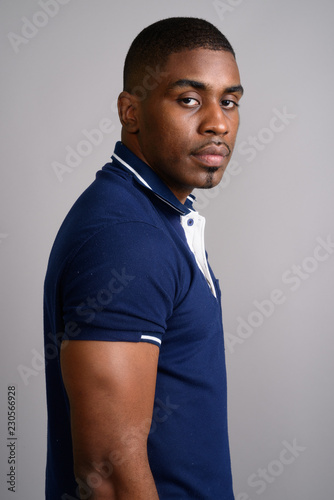 Young handsome African man wearing blue polo shirt against gray 